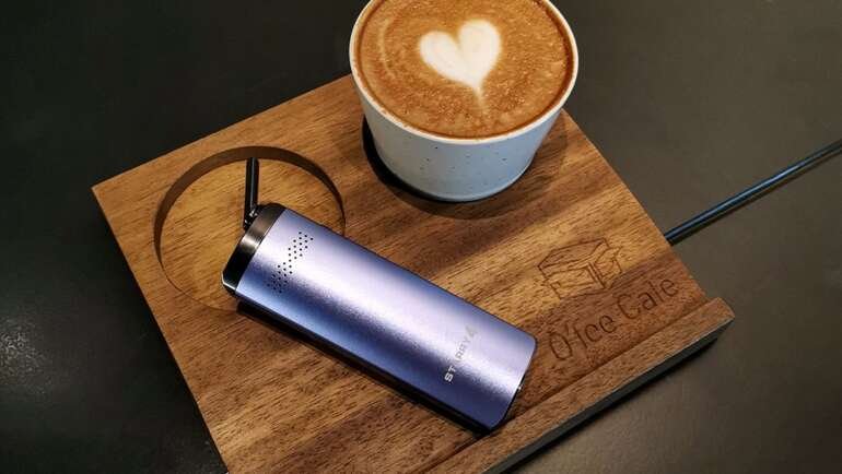 Günstige Vaporizer unter 100 Euro: tragbarer Cannabis-Vaporizer liegt neben Kaffeetasse auf einem Holztablett.