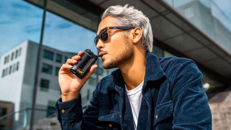 Top Premium-Vaporizer unter 200 Euro: Mann nutzt tragbaren Cannabis-Vaporizer im Freien.